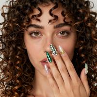 latina female with curly wavy hair and hazel eyes with Christmas tree accent nail with sparkly garlands and a gold star